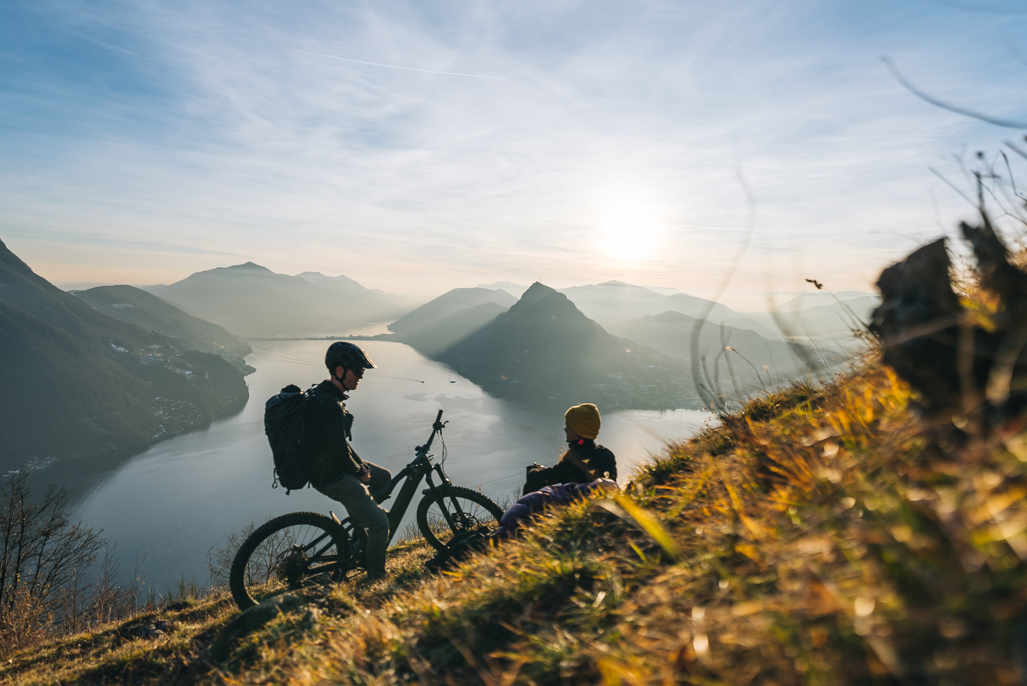 Fietsers die stilstaan met water en bergen in de achtergrond