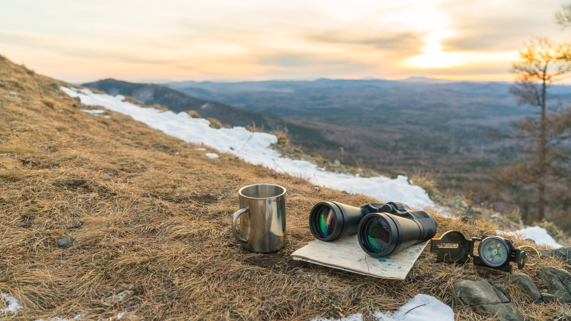 Verrekijker en kompas die op berg liggen