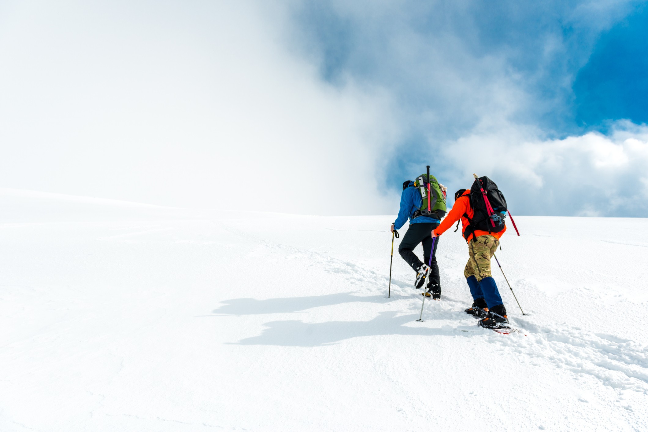 Twee wandelaars die een besneeuwde berg ophiken