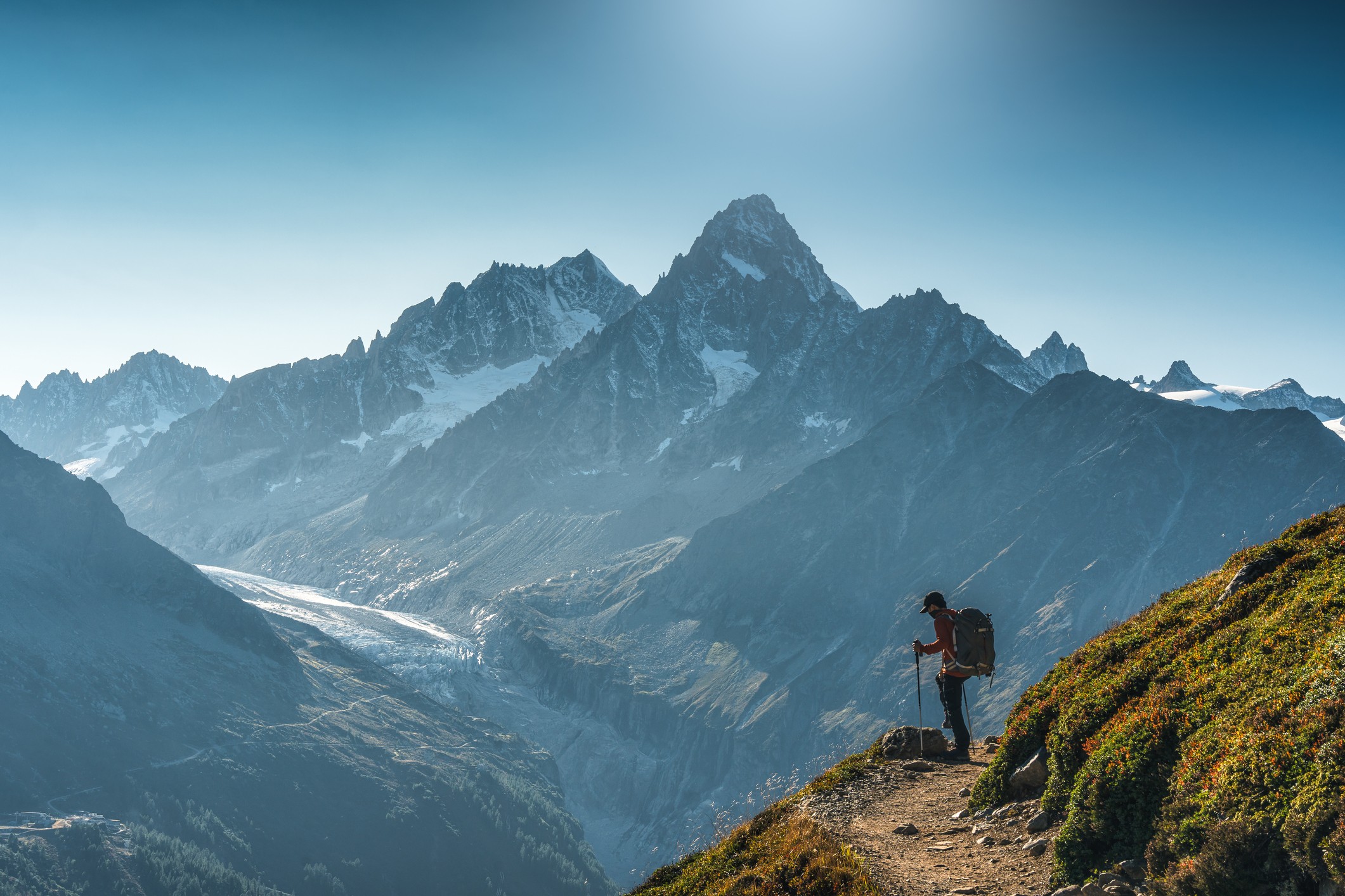 Persoon die op bergpad staat en uitkijkt op bergketen